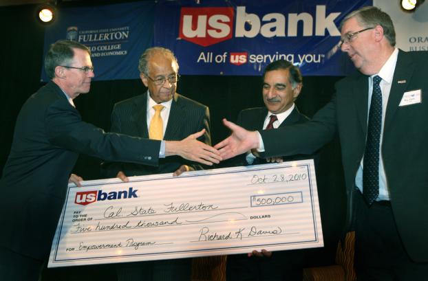 Richard Davis presents U.S. Bancorp check to Milton A. Gordon and Anil Puri as William R. Cave looks on.