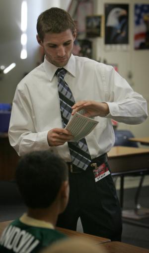 Andrew Holmes hands out test papers in a world history class