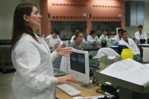Biologist Melanie Sacco runs explains the electrophoresis process to the students.