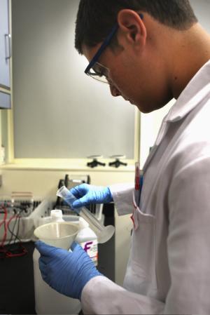 high school student Neil Yazma prepares gel for use in DNA experiments.