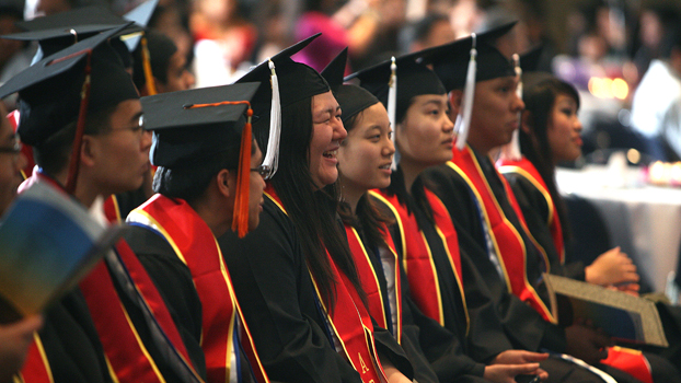 A row of Asian American graduates in their caps and gowns.