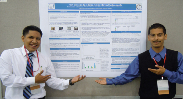 Two male students standing on either side of their poster that was presented at a fall SACNAS meeting.