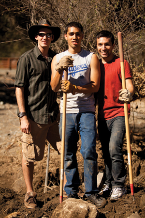 Three young men working with shovels and hoes.