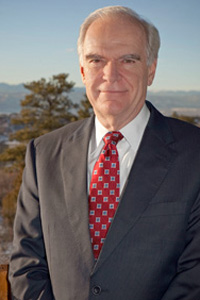 Richard Hartmann in business suit with red tie photographed with mountains behind him.