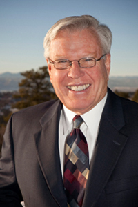 William Roberts in suit and tie with mountains as backdrop.