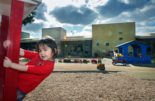 A toddler swings on a pole infront of the new Children's Center.