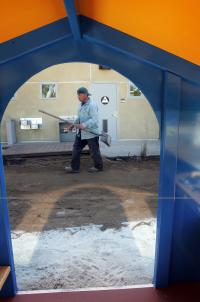 workman cleaning up at the children's center-seen through the doorway of a playhouse.