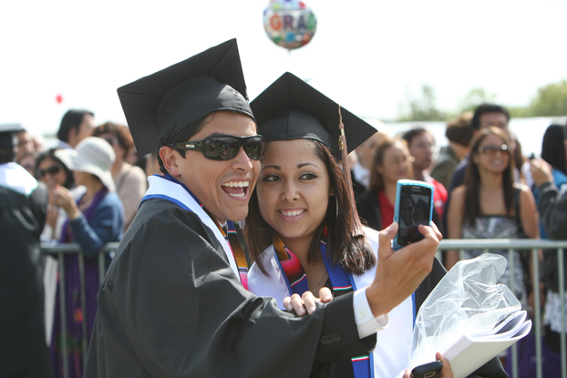 two hispanic students celebrating commencement.