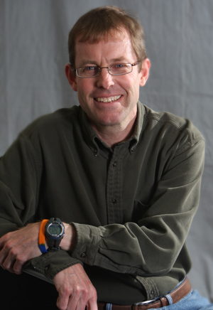 Scott Hewitt seated in front of a gray backdrop.