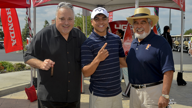 three golfers wait for their turn to tee off.