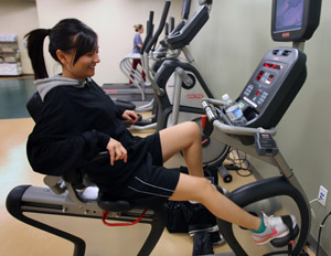 A female student works out on a stationary bicycle.
