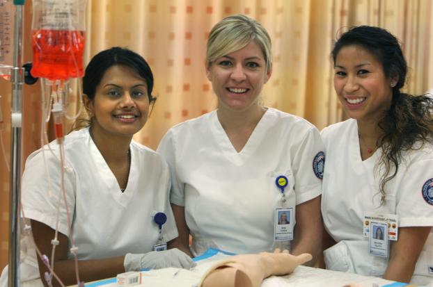 Three nursing students in the university's nursing lab.