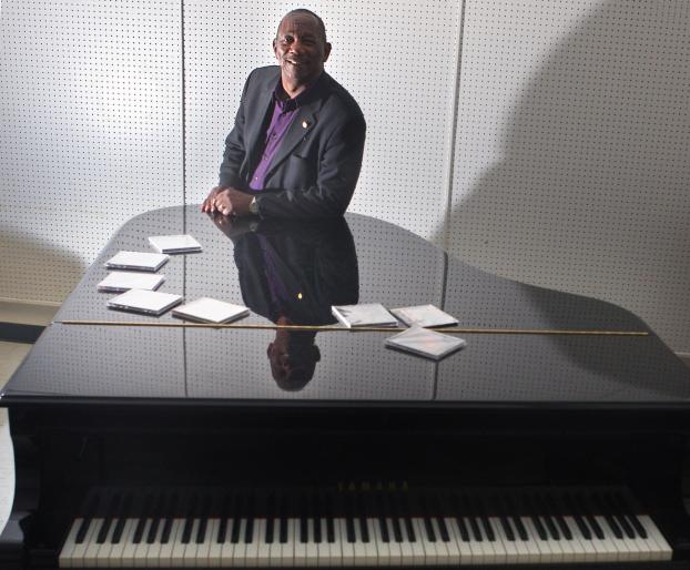 Stan L. Breckenridge poses with a piano and his CDs. Photo by Karen Tapia