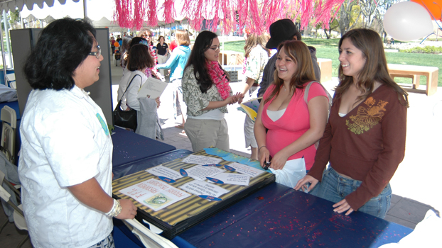 A staff members explains a program to a mother and daughter.