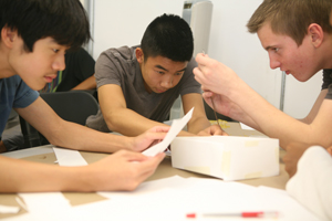 Three students work on a paper mousetrap.