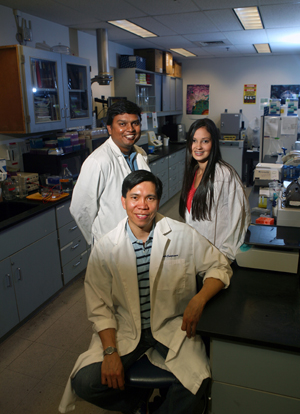 Math Cuajungco, seated, and students Vinod Valluri and Jessica Valadez infront of the lab they are working in.