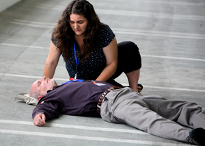 A young woman sits beside a “victim” laying on his back during the exercise.