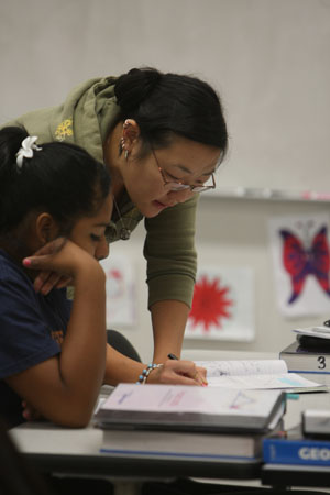 Candice Harrington stands next to one of the Project MISS students guiding her on a math problem.