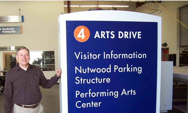George Holt stands beside one of the completed signs before installation on campus.