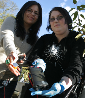 Two female students display the sensors used in a plant hydraulic study.