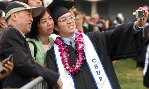 Asian family gets close together as the grad takes a photo with his cell phone.