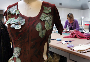 costume for production of Hansel and Gretel. In background is woman working on costume.