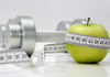 a barbell and a green apple wrapped with a tape measure.