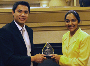 A man and a woman jointly hold a crystal award.