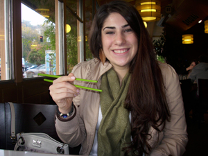 Tania Katbi holds green chopsticks while dining.