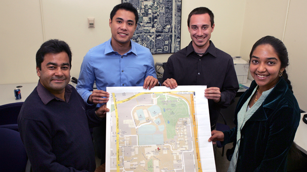 three students and thier professor hold a copy of a Google map of the campus.