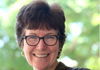 short-haired woman with glasses smiles into the camera.