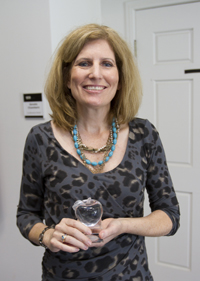 blond woman in a gray dress with blue necklace