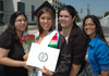 three women surround a graduate in commencement garb.
