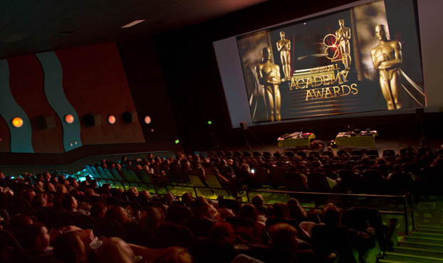 people in a threater with the opening of the Academy Awards on the screen