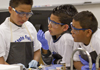 three young boys work on a lab experiment