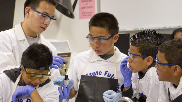 Youngsters watch as a college student conducts a lab experiment.