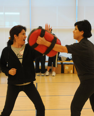 two women practice a defensive move during a RAD class.