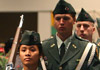 Three ROTC Cadets carrying rifles and flags