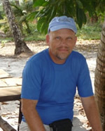 Brady Rhodes wearing a blue cap and t-shirt on a beach in Thailand.