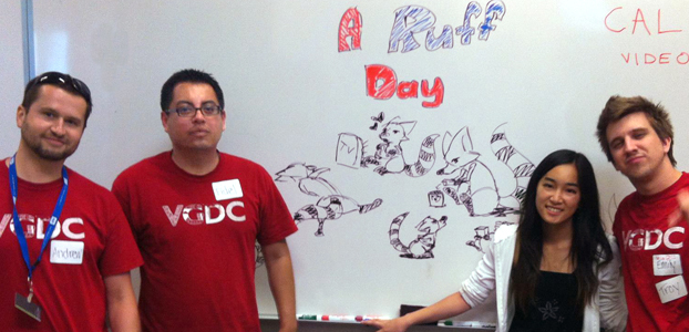 Four students stand before a white board with drawings from the game “A Ruff Day”