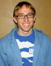 young man wearing glasses, blue t-shirt and blue sweatsuit jacket.
