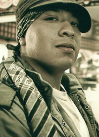 sepia-toned photo of a young hispanic wearing head bandana and cap.