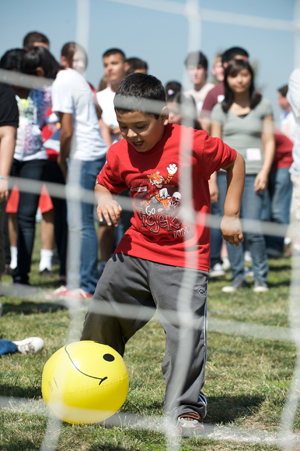 a little boy kicks a happy face ball into a soccer net