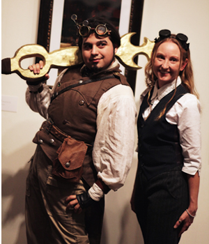 A young man in steampunk garb standing beside a young woman.