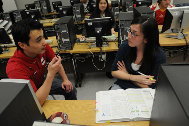 A student works with another student during a tax preparation program.