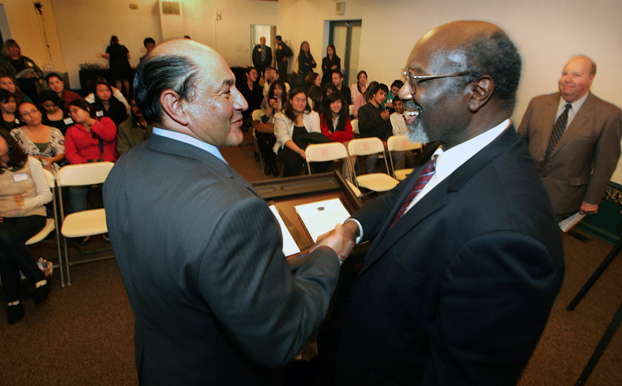 Sen. Lou Correa and Interim President Willie Hagan shake hands before a group of high school students.