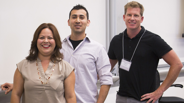 A woman and two men stand in front of whiteboards.