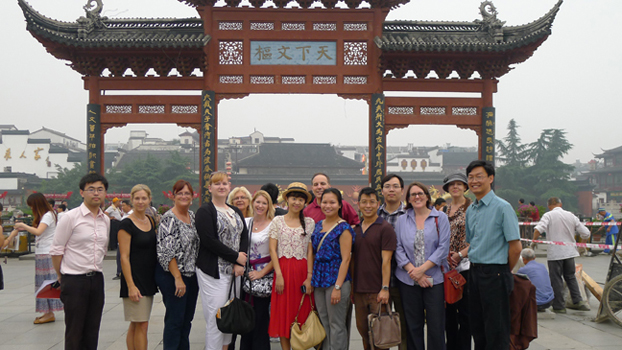 Group of men and women stand in front of Confucius Temple.