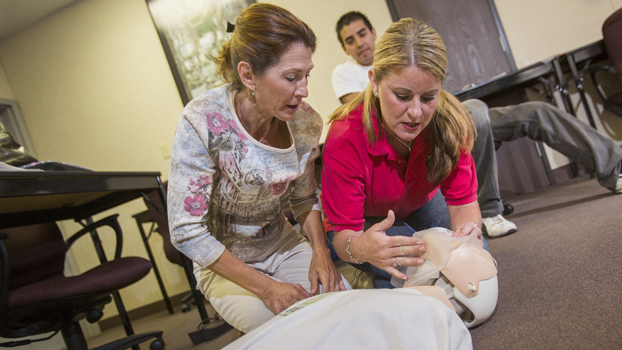 Two women work with a CPR training mannikin