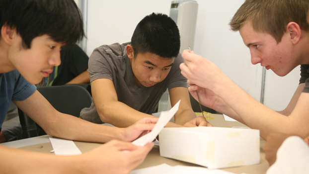 three young men working on a project.